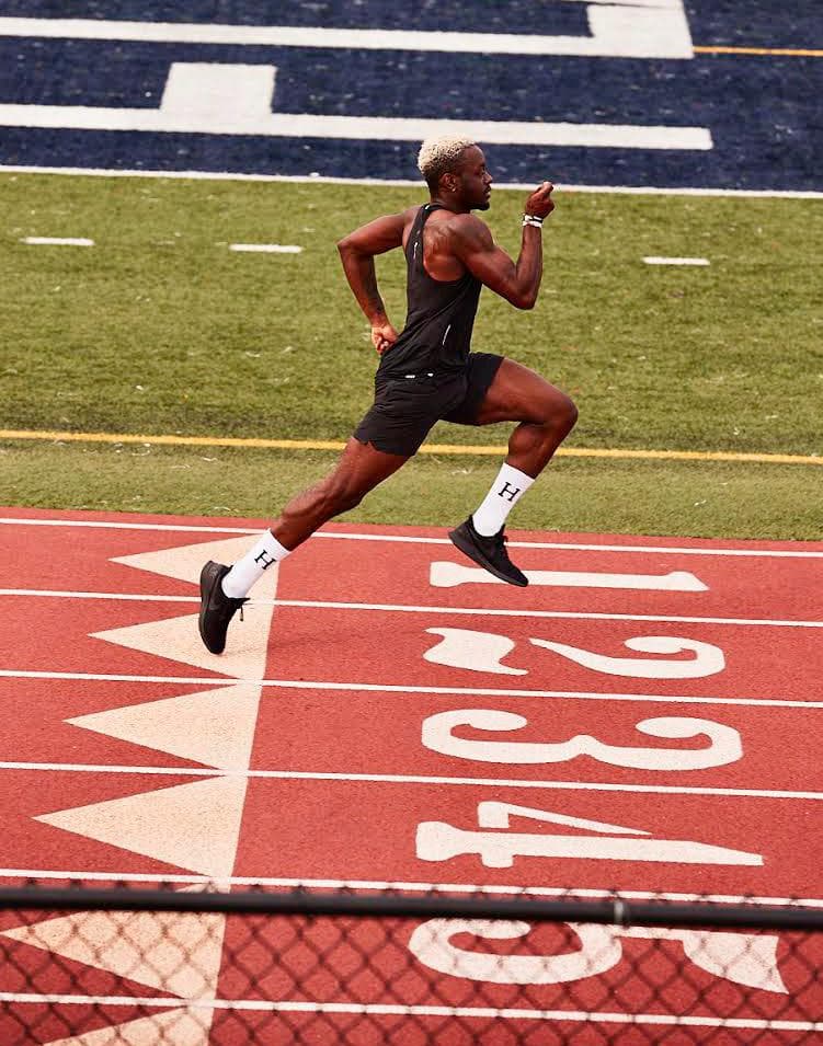 Le coach en pleine foulée de sprint au-dessus des numéros de couloir, en débardeur noir